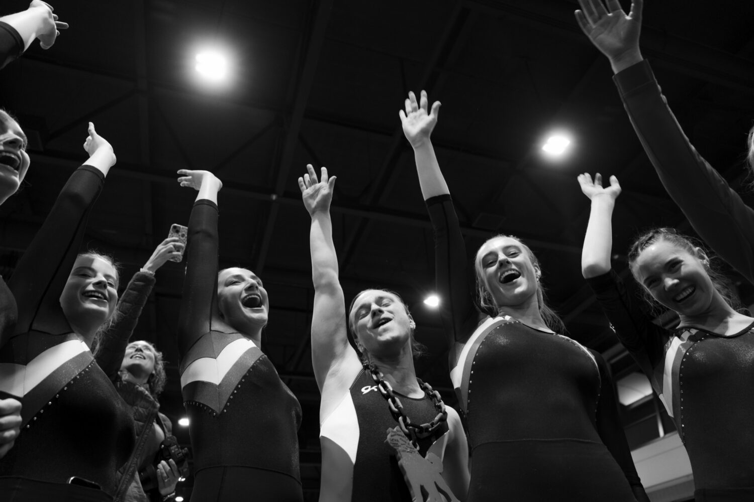 A team throws their hands in the air celebrating at a UCG meet