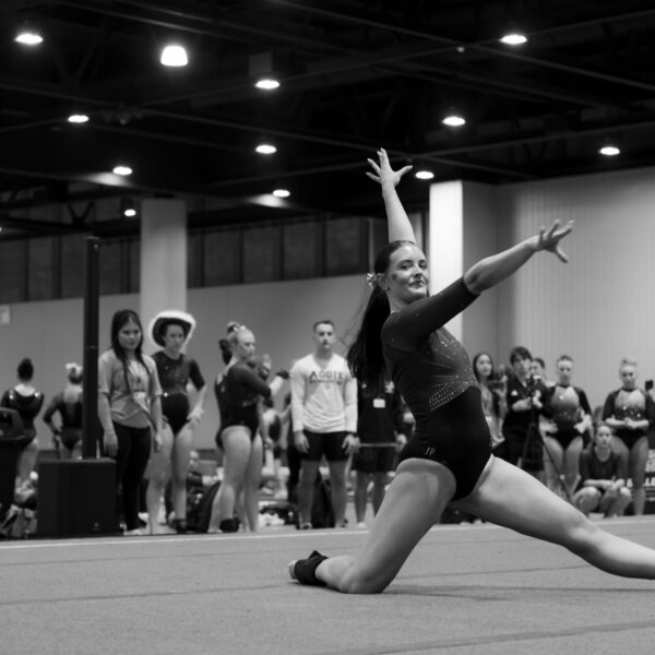 A gymnast holds a pose on floor at a UCG meet