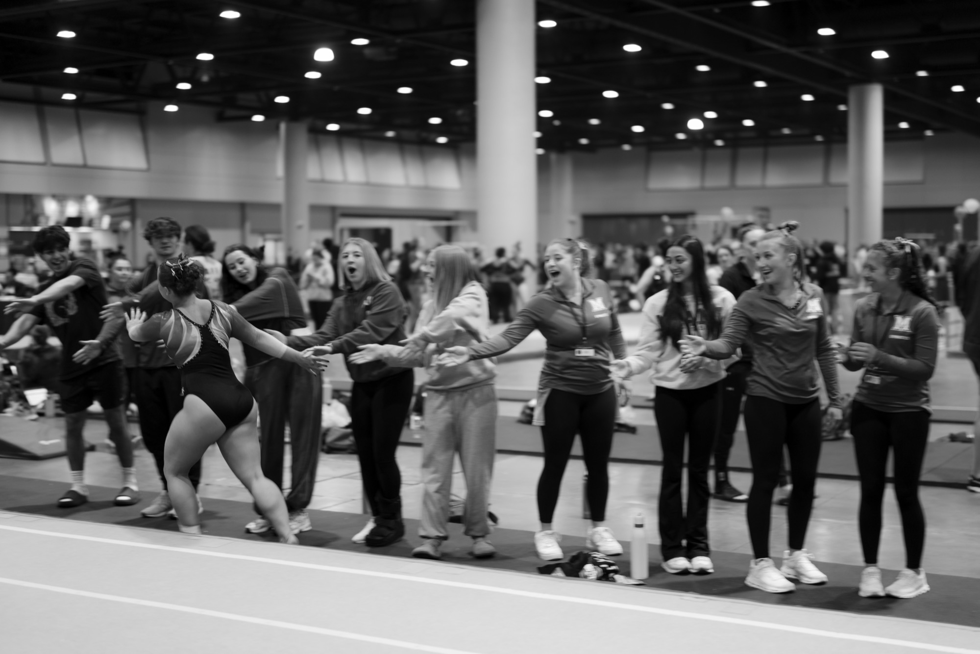 Adult gymnasts line up for high-fives at a UCG meet