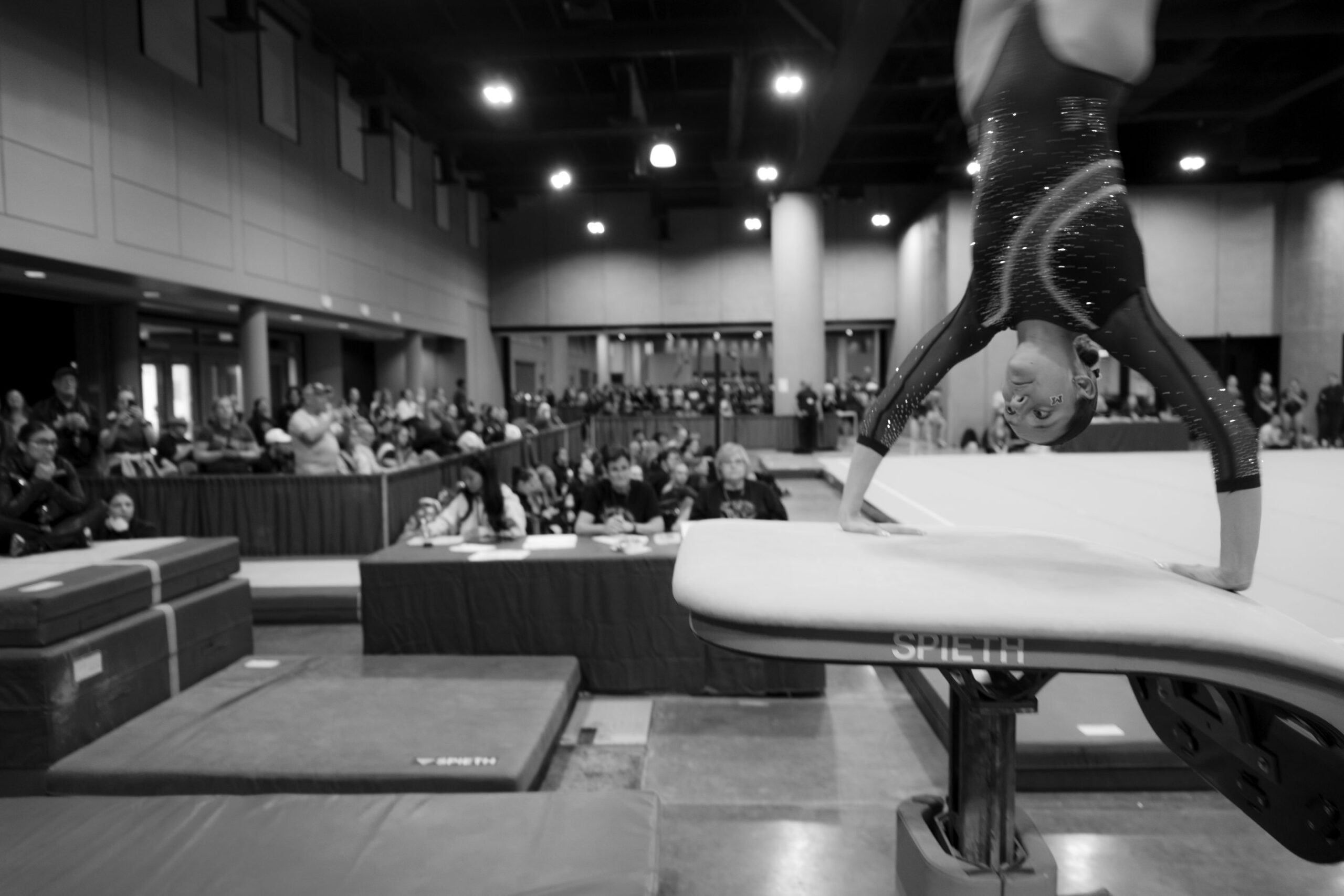 Judges follow a beam routine from the table at UCG Nationals