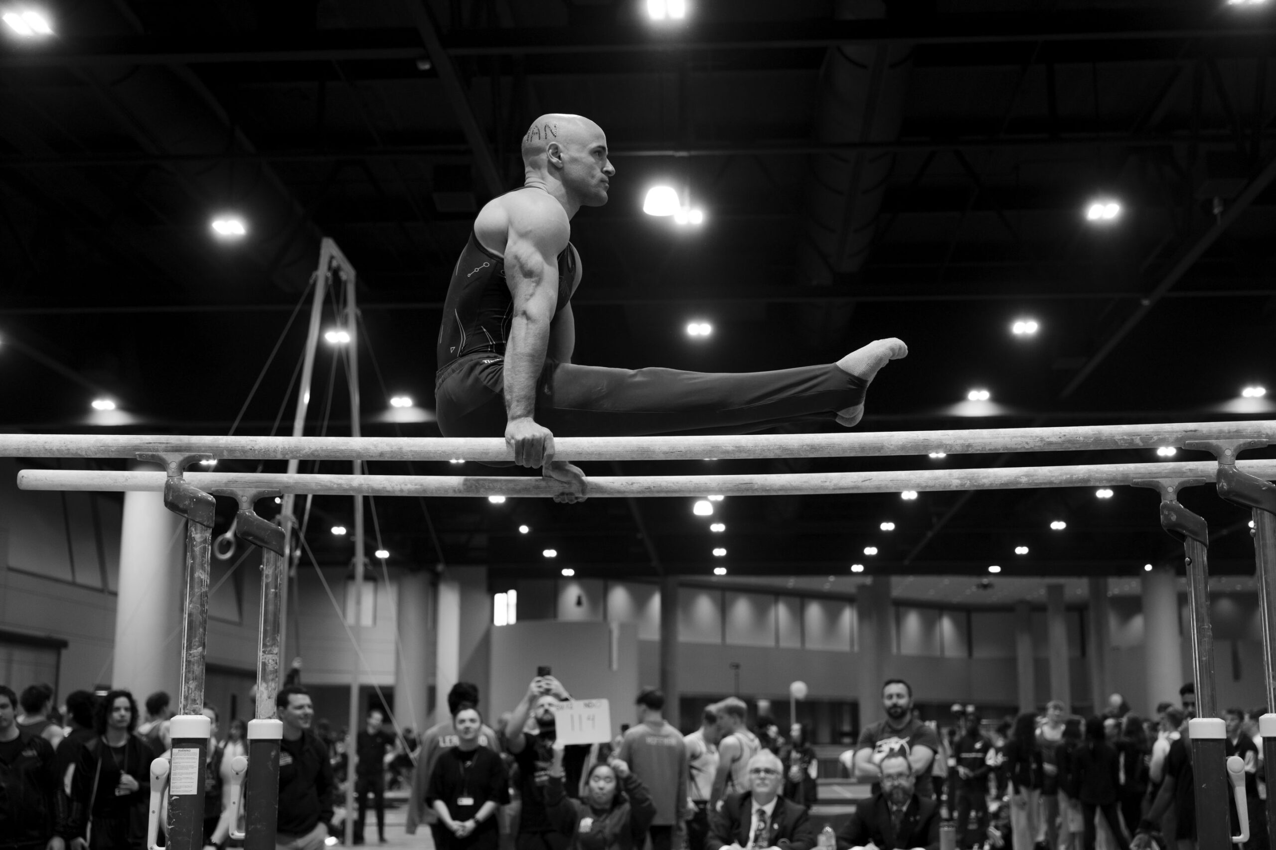 A gymnast holds a straddle support on the parallel bars at UCG Nationals