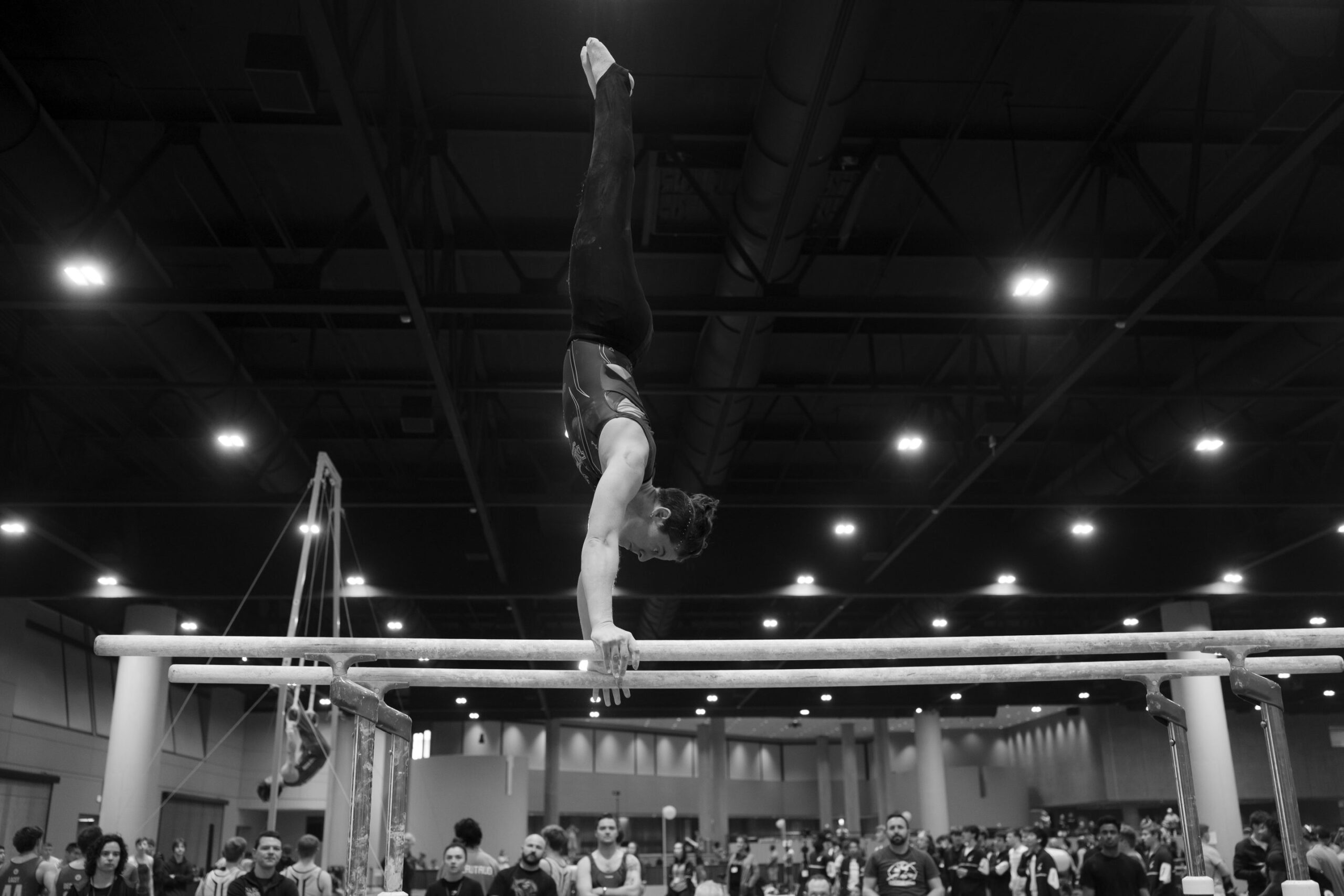 A gymnast hits a handstand on the high bar of the uneven bars at UCG Nationals